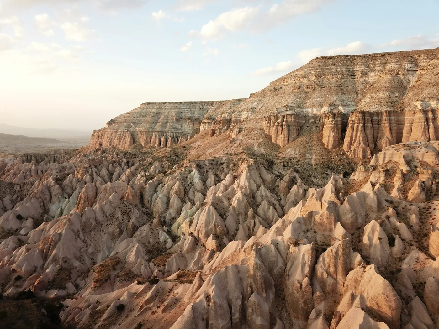 Čtyřkolky jedoucí do západu slunce nad údolími z tufových skal v Kappadokii